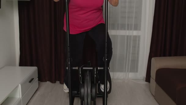 Femme âgée en vêtements de sport en utilisant orbitrek dans la chambre à la maison faire des exercices cardio entraînement sportif — Video