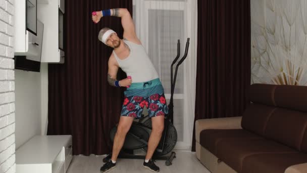 Esportista homem engraçado com barba faz exercícios de alongamento de treino, praticando esporte em casa — Vídeo de Stock