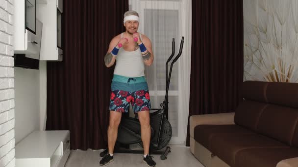 Смішний товстий спортсмен спортсмен у спортивному одязі робить спортивні вправи з гантелями вдома — стокове відео