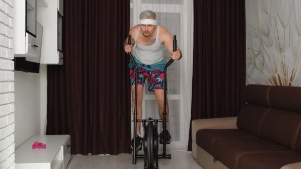 Zabawny sportowiec sportowiec facet trener na orbitrek nagrywanie sportu fitness cardio online vlog w domu — Wideo stockowe