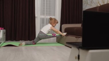 Spor sicim egzersizleri yapan, evde dizüstü bilgisayardan video eğitimi alan bir kız.