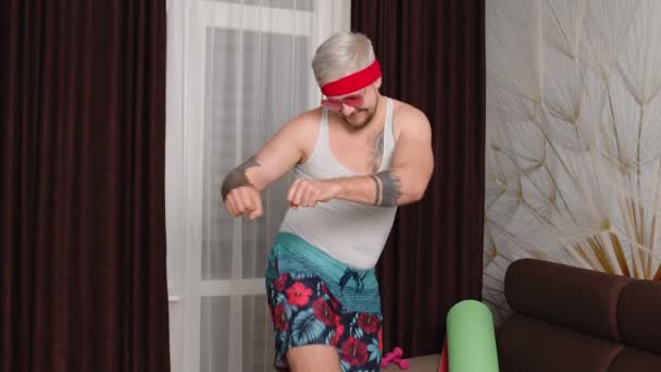 Мужчина в смешной одежде танцует дома, мужчина делает спортивные фитнес-кардио упражнения — стоковое видео