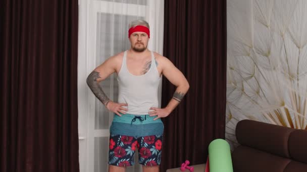Смешной спортсмен спортсмен с бородой делает упражнения на растяжку, занимаясь спортом дома — стоковое видео