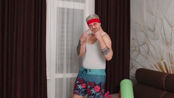 Sportsman retro bearded guy in funny clothes, man showing rock and roll gesture, dancing at home — Stock Video