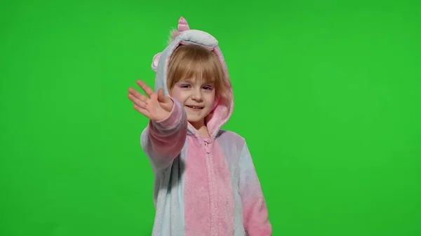 Bambina bambina sorridente, salutando agitando, ciao o ciao con mano in pigiama unicorno sul tasto chroma — Foto Stock