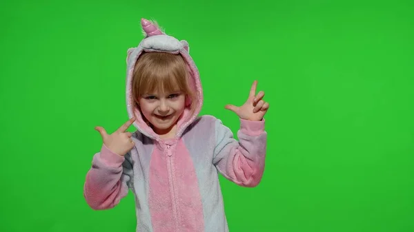 Kis szőke gyermek lány mosolyog, tánc, ünneplő unikornis pizsama jelmez krómkulcs — Stock Fotó