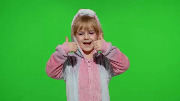 Niña sonriendo, mostrando los pulgares hacia arriba gesto, de acuerdo signo en pijama unicornio en croma key — Foto de Stock