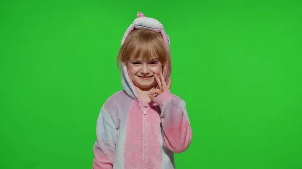 Petite fille enfant souriant, montrant les pouces levés, ok geste, signe d'accord en pyjama licorne sur la touche chroma — Photo