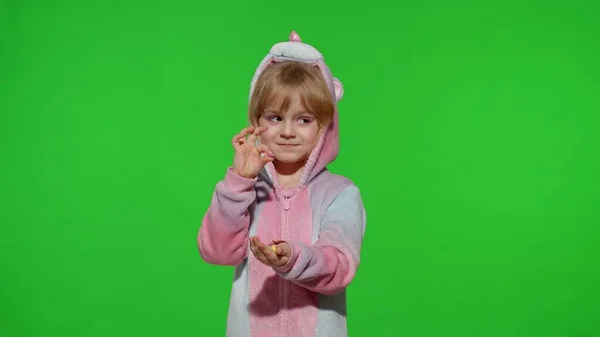 Bambino sorridente, godendo mangiare dolci caramelle dessert in costume unicorno sul tasto chroma — Foto Stock