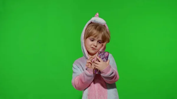 Excited little child girl in unicorn pajamas using mobile cell phone, found out great big win news — Stock Photo, Image