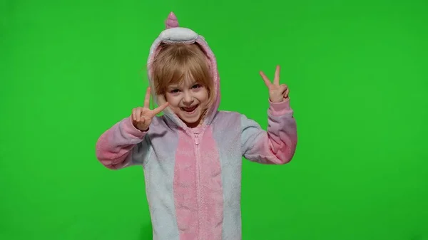 Menina criança em pijama unicórnio fazendo caras engraçadas bobas, brincando, mostrando a língua na tecla chroma — Fotografia de Stock