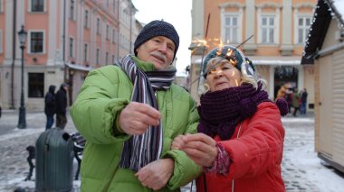 Kıdemli çift yanan maytaplı bengal ışıkları ile şehir merkezinde yıldönümünü kutluyor.