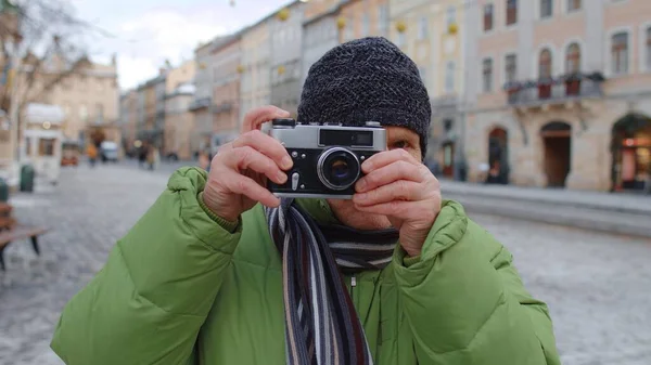 Hombre mayor tomando fotos con cámara fotográfica, usando dispositivo retro al aire libre en el centro de la ciudad de invierno —  Fotos de Stock