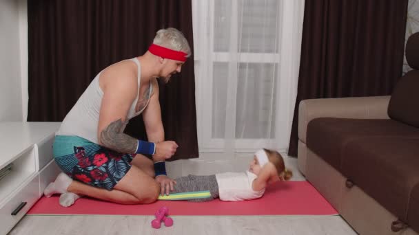 Šedovlasý vousatý sportovec chlap trenér otec dělá břišní cvičení s dcerou doma na podložce — Stock video