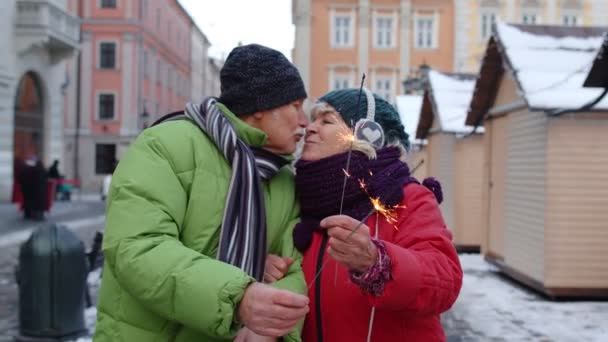 Couple aîné avec des étincelles brûlantes bengale lumières célébrant anniversaire, faire un baiser dans la rue — Video