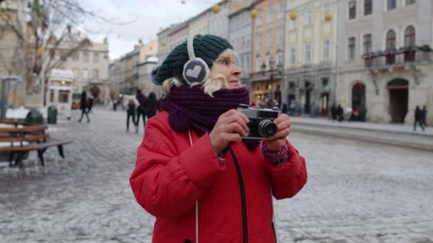 Mujer mayor abuela turista tomar fotos con cámara fotográfica, sonriendo con dispositivo retro — Vídeo de stock
