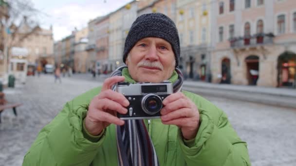 Senior man tar bilder med fotokamera, med hjälp av retro enhet utomhus i vintern centrum — Stockvideo