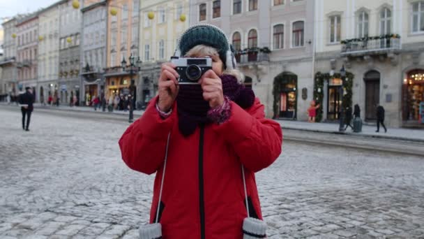 Senior kvinna turist tar bilder med fotokamera, med hjälp av retro enhet i vintern centrum — Stockvideo
