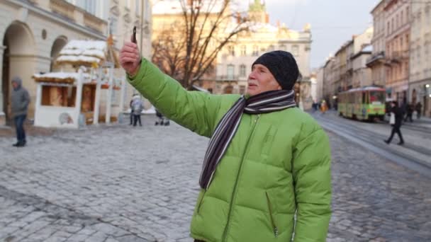 Senior man turist tar selfie, gör online videosamtal med smart telefon i vintern centrum — Stockvideo