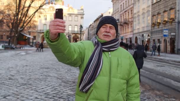 Senior man turist tar selfie, gör online videosamtal med smart telefon i vintern centrum — Stockvideo