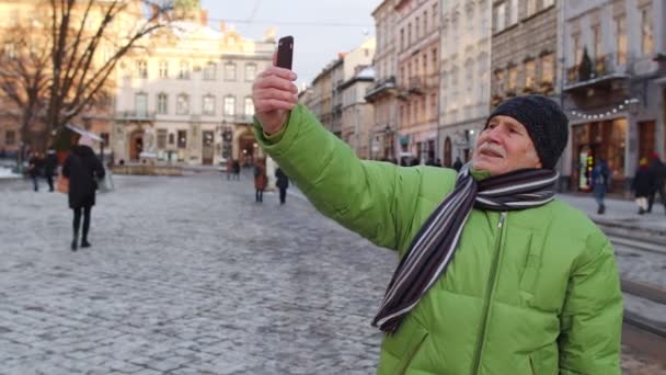 ผู้ชายอาวุโสนักท่องเที่ยวเดินทางเดินถ่ายรูปเซลฟี่ในเมืองฤดูหนาวยุโรป — วีดีโอสต็อก