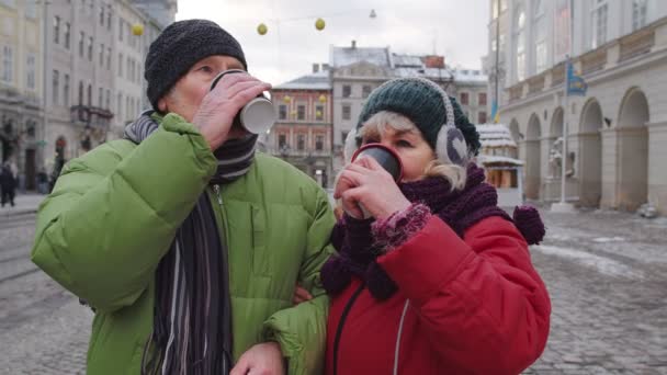 Senior turisták nagymama nagypapa utazás, ivás forró ital forralt bor a város központjában — Stock videók