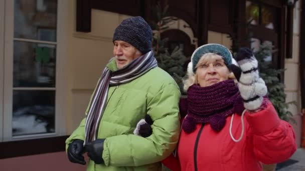 Μπροστά άποψη του ηλικιωμένου ζευγαριού τουριστών άντρας γυναίκα περπάτημα, ομιλία, χειρονομίες στην πόλη χειμερινές διακοπές — Αρχείο Βίντεο