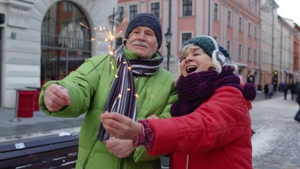 Starší pár s hořícími jiskry bengálské světla slaví výročí na ulici centra města — Stock video