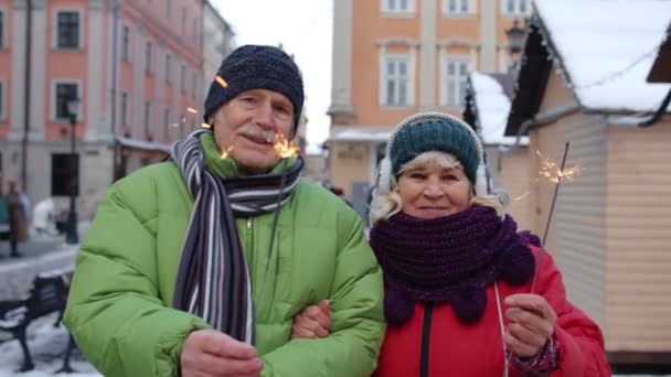 Starsza szczęśliwa para z płonącymi ogniami bengalskie światła świętujące urodziny na ulicy centrum miasta — Wideo stockowe