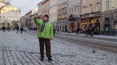 Kış şehir merkezinde kıdemli büyükbaba turist akıllı telefonuyla online video görüşmesi yapıyor.
