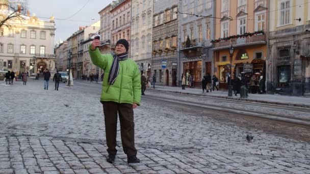 Senior man farfar turist gör online videosamtal med smart telefon i vintern centrum — Stockvideo