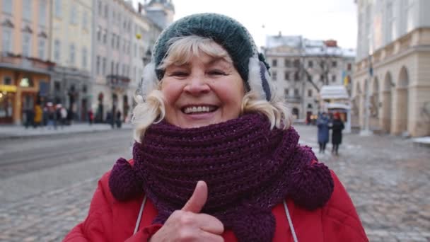 Snygg gammal äldre kvinna turist leende, visar tummen upp i vinter centrum av Lviv, Ukraina — Stockvideo