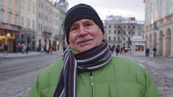 Portrait of old senior man tourist smiled, looking at camera in winter city center of Lviv, Ukraine — Stok Video