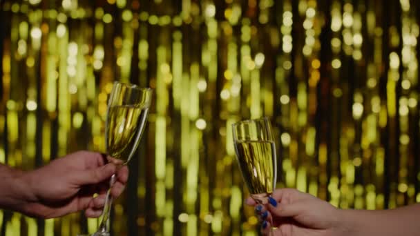 Dos manos con copas de vino de champán o cócteles haciendo vítores, levantando tostadas sobre fondo dorado — Vídeos de Stock