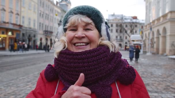 Стильная пожилая туристка улыбается, показывая большой палец в зимнем центре Львова, Украина — стоковое видео