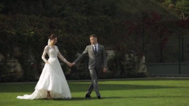 Sevgili yeni evliler, beyaz gelin damat parkta yürüyor, el ele tutuşuyorlar, düğün çifti ailesi.