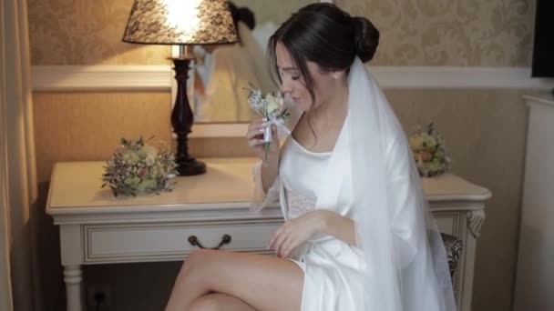 Novia en vestido de tocador, velo y en una túnica de seda con ramo de flores para el novio, mañana de bodas — Vídeos de Stock