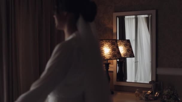 Υπέροχη νύφη σε λευκό φόρεμα μπουντουάρ πηγαίνει στο μπαλκόνι και ανοίγει κουρτίνες σε δωμάτιο ξενοδοχείου ή διαμέρισμα — Αρχείο Βίντεο