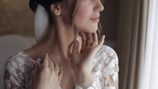 Novia en vestido blanco permaneciendo cerca de la ventana y tocando su cara, preparativos de la mañana de boda en casa — Vídeos de Stock