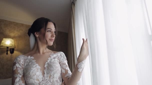 Noiva em vestido boudoir perto da janela. Preparativos da manhã de casamento. Mulher de vestido de noite e véu — Vídeo de Stock