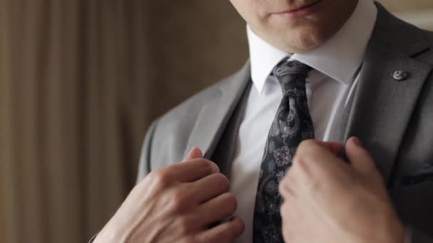 Jóképű vőlegény üzletember szürke kabátot visel otthon a nappaliban, fehér ing fekete nyakkendővel — Stock videók