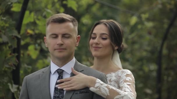 Schöne frischvermählte kaukasische Braut umarmt Bräutigam im Park macht Kuss, Hochzeitspaar Familie umarmt — Stockvideo