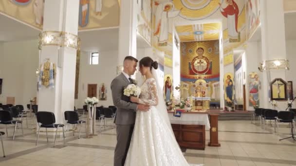 Adorável família recém-casados casal noiva abraçando noivo em uma igreja antiga, cerimônia de casamento, casamento — Vídeo de Stock