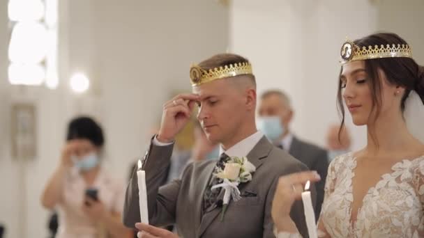 Novomanželé. Nevěsta a ženich stojí v kostele se svíčkami v rukou. Svatební obřad — Stock video