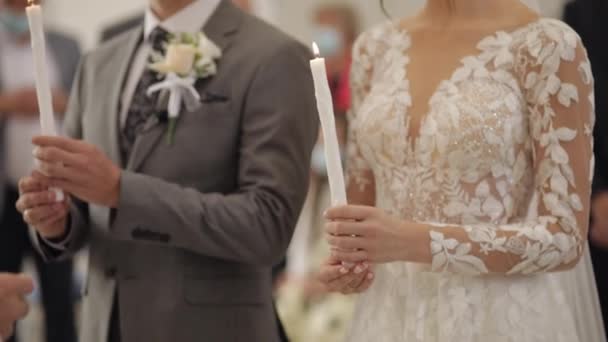 Recém-casados. Noiva e o noivo estão na igreja, segurando velas em suas mãos. Cerimônia de casamento — Vídeo de Stock