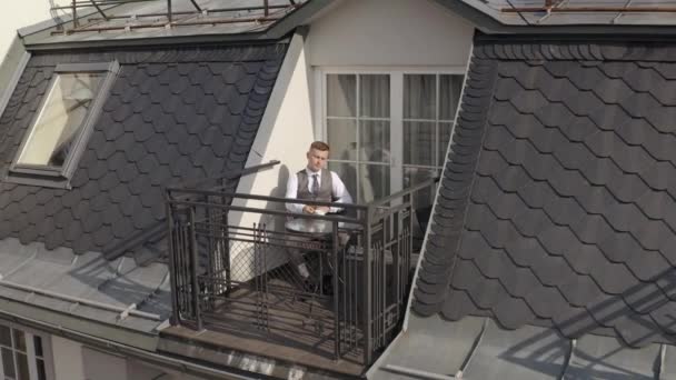 Άντρας γαμπρός επιχειρηματίας πίνει καφέ από ένα λευκό κύπελλο στο μπαλκόνι στο σπίτι το πρωί του γάμου — Αρχείο Βίντεο