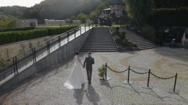 Sevgili yeni evliler, beyaz gelin damat parkta yürüyor, el ele tutuşuyorlar, düğün çifti ailesi.
