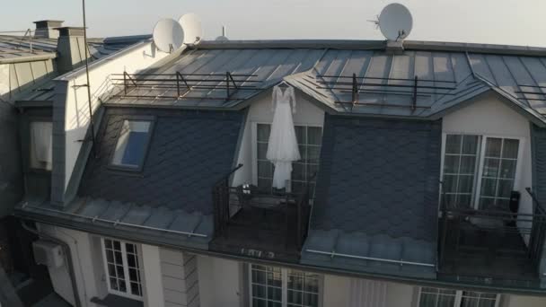 Witte trouwjurk hangt op speciale hanger in deuropening van balkon van luxe huis, luchtfoto uitzicht — Stockvideo