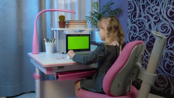 เด็กนักเรียนหญิงเรียนรู้บทเรียนที่บ้านโดยใช้คอมพิวเตอร์แล็ปท็อปดิจิตอลที่มีหน้าจอสีเขียว — วีดีโอสต็อก