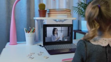 Sevimli çocuk video dersi izliyor, dijital dizüstü bilgisayar kullanıyor, internette ödev yapıyor.